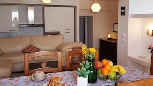 A cozy living room with a sofa, chairs, a dining table with a fruit bowl, and a vase with flowers. - House Betta (Genoa)