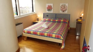 A small bedroom with a bed, a nightstand, a lamp, and a window. - House Asfodelo (Genoa)