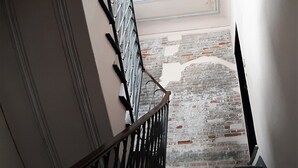 A staircase with a metal railing and a brick wall with a white outline. - Sea Attic (Noli)