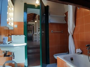 A bathroom with a sink, mirror, and bathtub. - Sea Attic (Noli)