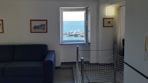 A room with a view of the sea, a sofa, a bed, and a phone on the wall. - La Torre (Bogliasco)