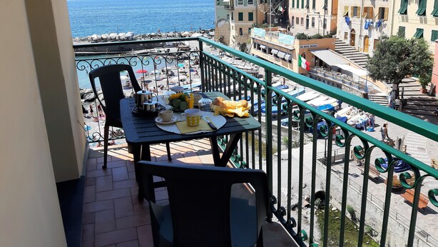 A balcony with a table set for breakfast, overlooking a beach and a coastal town. - La Torre (Bogliasco)