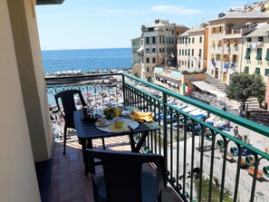 A balcony with a table set for breakfast, overlooking a beach and a coastal town. - La Torre (Bogliasco)