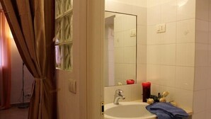 Un baño con lavamanos, espejo y perchero para toallas.
