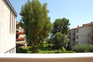 A courtyard with a lawn, trees, and buildings with balconies. - Casa Azalea (Sanremo)