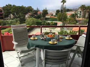 A balcony with a table set for breakfast, overlooking a tennis court and residential buildings. - Casa Azalea (Sanremo)