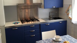 A compact kitchen with a stainless steel range hood, a sink, and blue cabinets. - Casa Mon Amour (Moneglia)