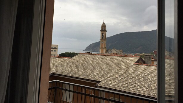 A view of a coastal town with a prominent clock tower and a mountain in the background. - Casa Mon Amour (Moneglia)