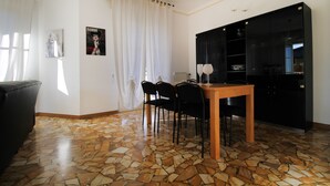 A dining area with a table and chairs, a black cabinet, and a tiled floor. - House Bella (Arenzano)