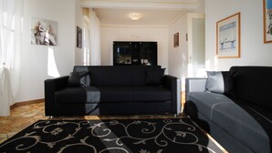 A living room with two black sofas, a patterned rug, and artwork on the walls. - House Bella (Arenzano)