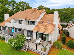 Une maison moderne à deux étages, dotée d’un toit en tuiles, d’un balcon avec mobilier d’extérieur et d’un jardin bien entretenu.