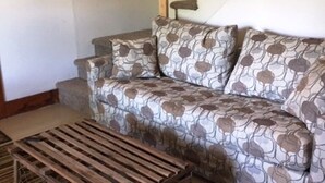 Een woonkamer met een gestreept bankstel, een houten bankje en een trap.