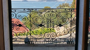 A balcony with a metal railing overlooking a coastal view.