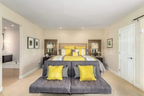 A bedroom with a large bed, bedside tables, a sofa, and a door.