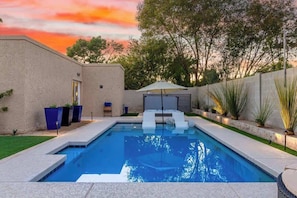 A rectangular swimming pool with a white deck, surrounded by a low wall and a grassy area. - Executive Retreat|Pool & Spa|AZ Canal Trail|BBQ (Scottsdale)