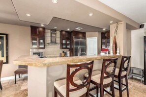 Una cocina moderna con una isla central, armarios oscuros y un refrigerador de acero inoxidable.