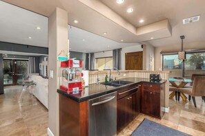 A modern kitchen with a central island, stainless steel appliances, and a dining area with a wooden table and chairs.