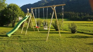 A swing set in a grassy field with a mountain in the background. - Schneiderbauer (Waidring)