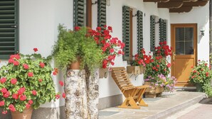 A building with a white facade, green shutters, and a wooden bench outside. - Schneiderbauer (Waidring)