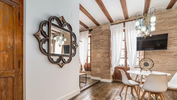 A dining area with wooden flooring, a chandelier, and a TV mounted on the wall. - MY LOFT 4 YOU RUZAFA STYLE II (Valencia)