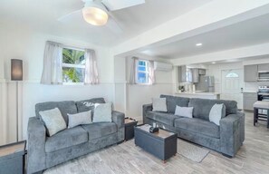 A modern living room with two grey sofas, a coffee table, and a ceiling fan.