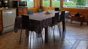 Una cocina con armarios de madera, una mesa de comedor con sillas, una cafetera, un microondas y vistas a zonas verdes.