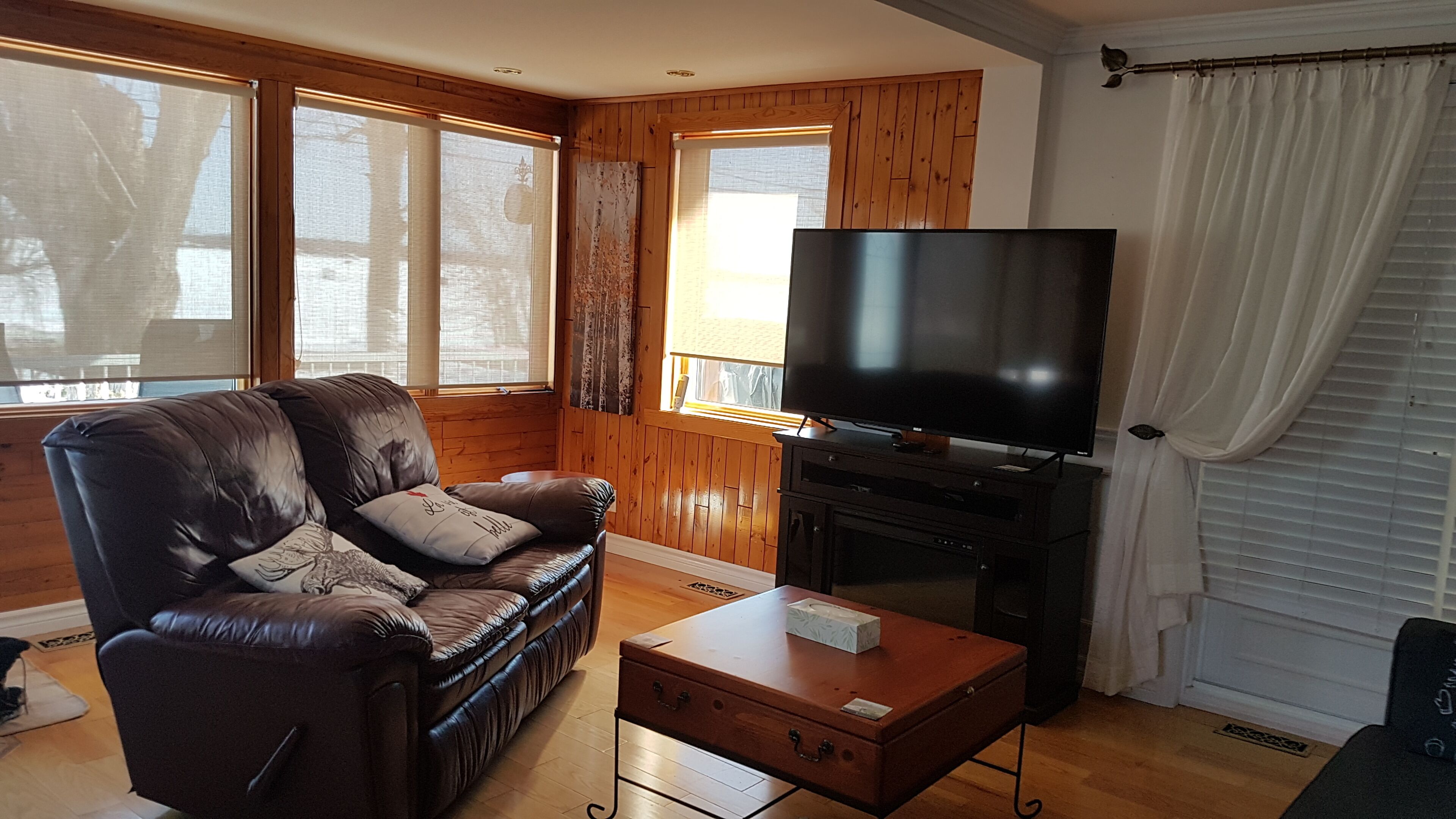 A living room with a leather sofa, a flat-screen TV, and a wooden cabinet.