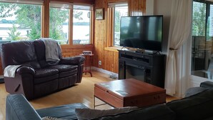 Una sala de estar con un sofá de cuero, una mesa de centro de madera, un televisor y una chimenea.
