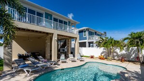 A two-story house with a swimming pool, outdoor seating, and a covered patio. - New 4BR Oasis: Walk to Beach, Pool, Pet-Friendly! (Fort Myers Beach)