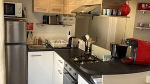 A compact kitchen with a stainless steel refrigerator, a microwave, a gas stove, and wooden cabinets. - Rent mobile home 6pers 40 m2 from 250 € per week (pont aven)