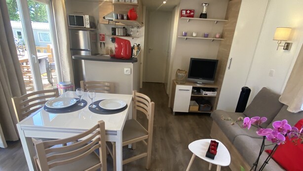 A compact living space with a dining area, kitchenette, and seating area. - Rent mobile home 6pers 40 m2 from 250 € per week (pont aven)