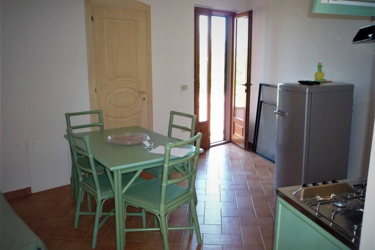 A small kitchen with a dining table and chairs, a refrigerator, and a stove.