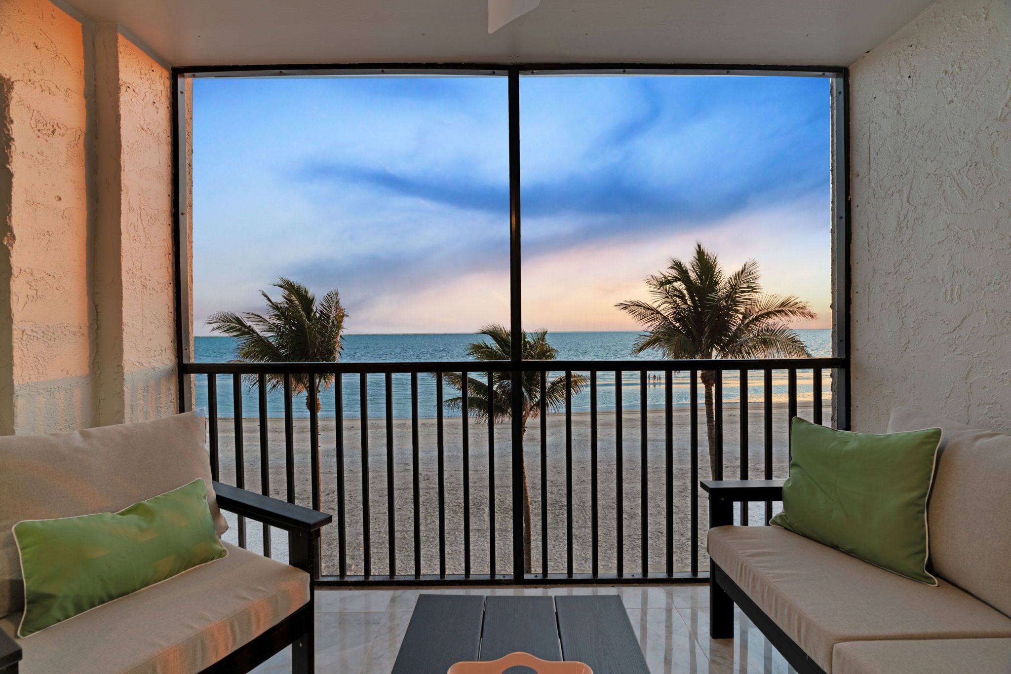 Un balcon avec vue sur la plage et les palmiers.