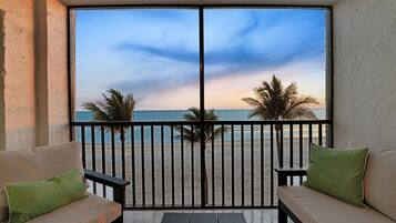 Een balkon met uitzicht op het strand en palmbomen.
