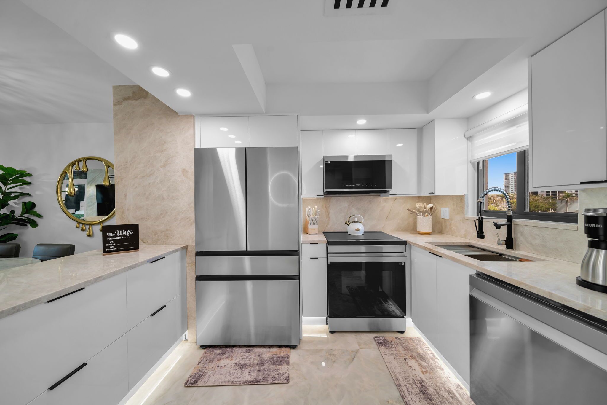 A modern kitchen with stainless steel appliances, a marble countertop, and a view of the city.