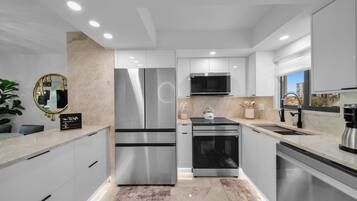 A modern kitchen with stainless steel appliances, a marble countertop, and a view of the city.