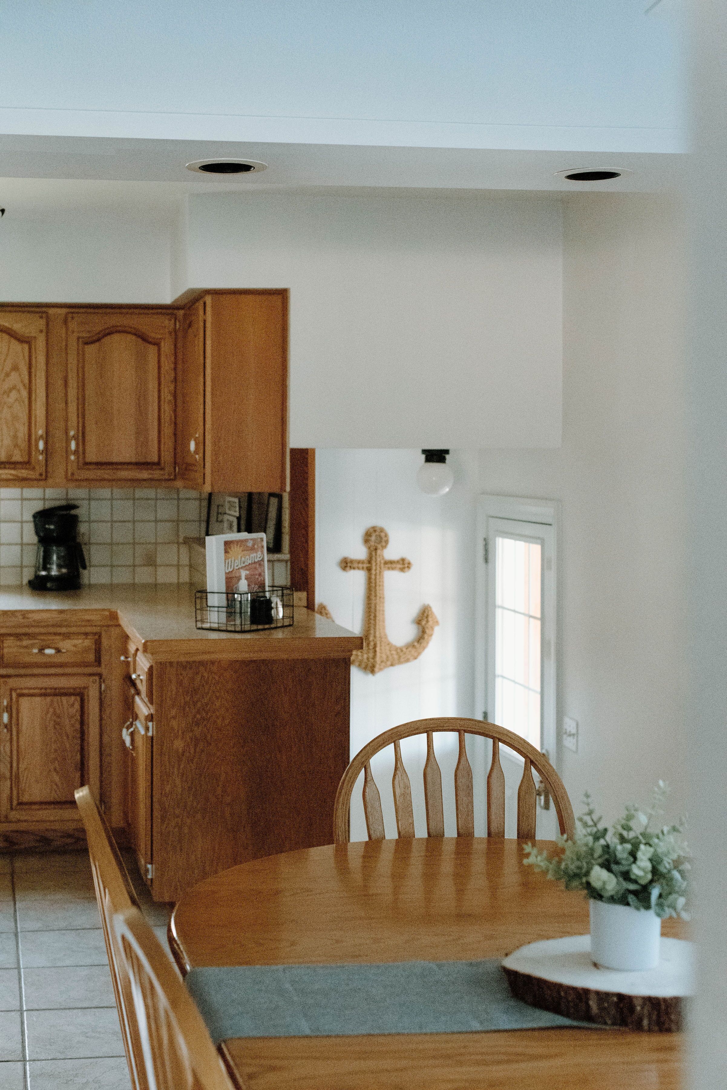A kitchen with wooden cabinets, a coffee maker, and a potted plant on the table.