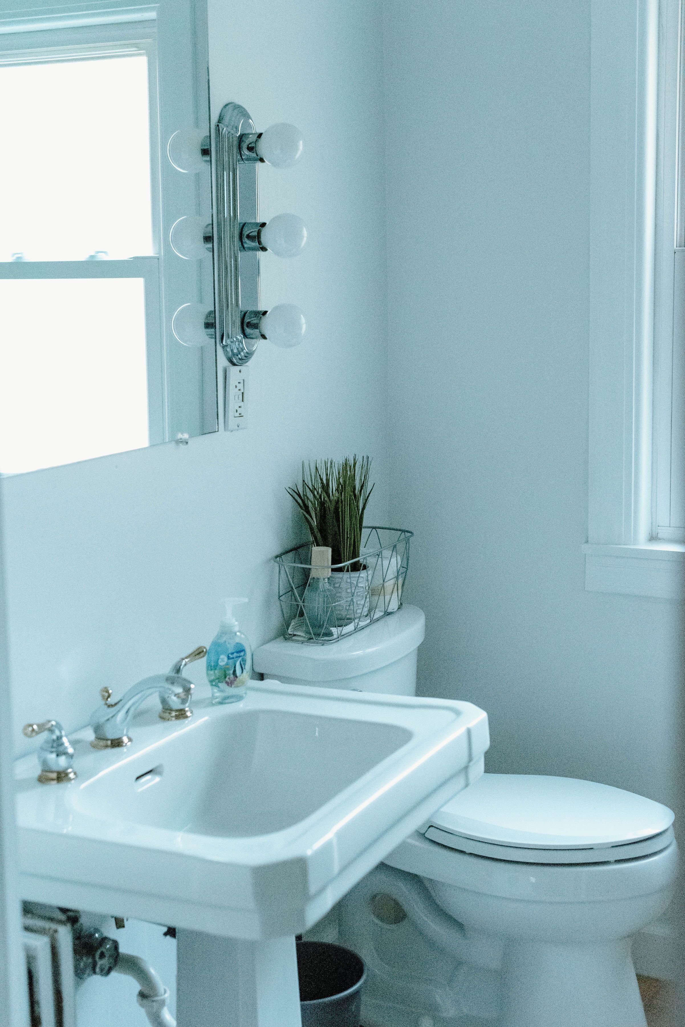 A bathroom with a white sink, a toilet, and a mirror with lights.
