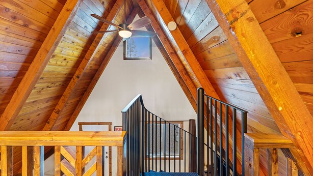A wooden attic room with a sloped ceiling, a ceiling fan, and a small window. - A-frame at Spotted Bear Retreat (Martin City)