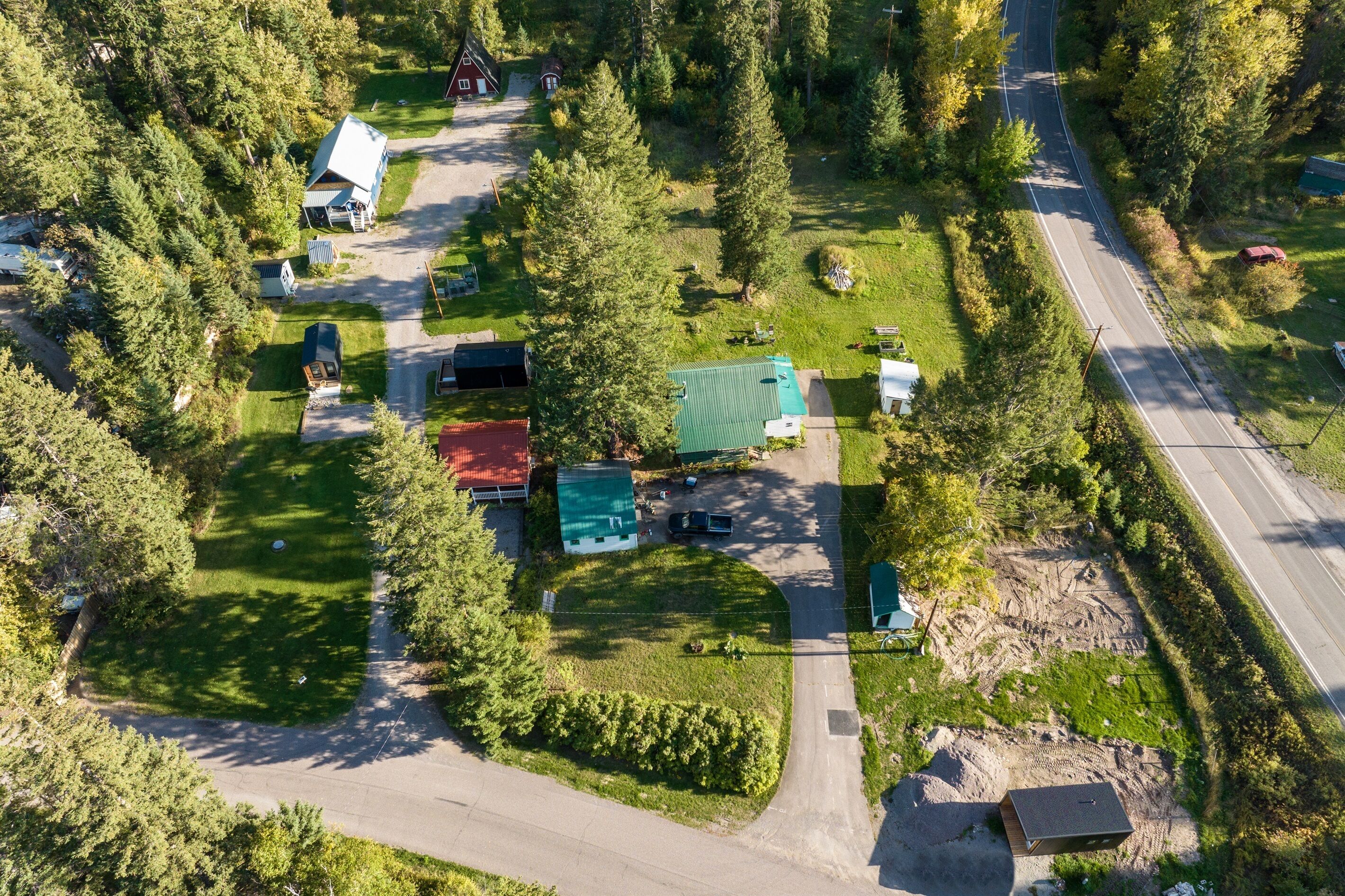 An aerial view of a rural property with multiple buildings, a road, and surrounding greenery.