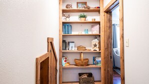 A narrow hallway with wooden shelves displaying various items like books, baskets, and decorative objects.