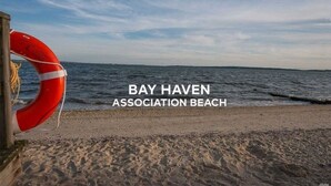 Une bouée de sauvetage sur une plage, avec l’inscription « PLAGE DE L’ASSOCIATION BAY HAVEN ».