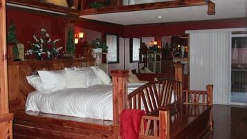 A wooden bed with white bedding, a red throw blanket, and a wooden bench.