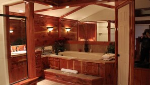 A wooden bathroom with a large bathtub, a double sink, and a mirror. - Lazy G #1 Honeymoon Suite (Union Grove)