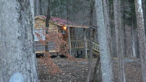 Une cabane avec une façade en bois, une véranda et un escalier apparent menant à l’entrée.