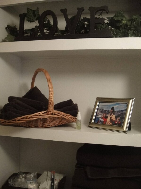 A shelf with a wicker basket, a framed photo, and a small bottle.