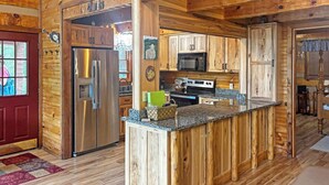 A wooden cabin interior with a kitchen featuring a stainless steel refrigerator, a microwave, and a stove.