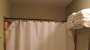 Une salle de bain avec un rideau de douche blanc, des toilettes et un lavabo équipé d’un porte-serviettes.