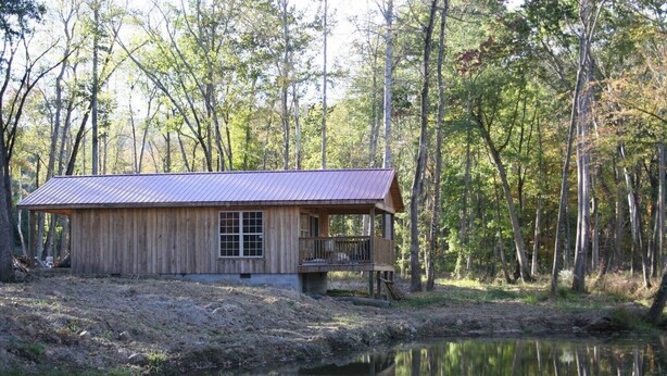 A rustic cabin with a metal roof, a wooden deck, and a window. - Lazy G Cabin #4 Creeks Edge (Union Grove)