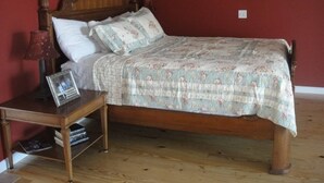 A wooden bed with floral bedding, a nightstand with a lamp, and a framed photo. - Lazy G Cabin #4 Creeks Edge (Union Grove)
